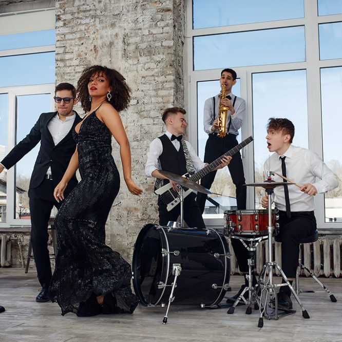 Jazz band performing with a singer and musicians playing saxophone, drums, and guitar in a stylish loft with large windows.
