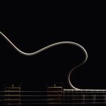 Close-up of a jazz guitar's body and strings in low light, highlighting its elegant curves and golden hardware.