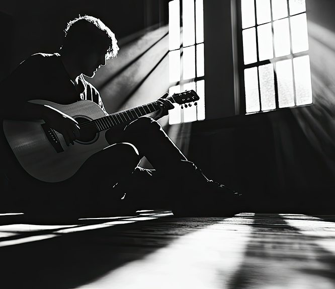 Kelly Joe Phelps playing an acoustic guitar on stage during a live jazz performance, with a spotlight highlighting his focused expression.